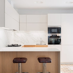 Diseño de cocina en U, contemporánea, con fregadero de un seno, armarios con paneles lisos, puertas de armario blancas, salpicadero blanco, salpicadero de losas de piedra, península, suelo multicolor y encimeras blancas