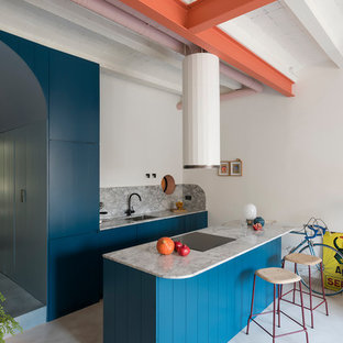 Foto de cocina de galera, industrial, con armarios con paneles con relieve, puertas de armario turquesas, salpicadero verde, electrodomésticos con paneles, una isla, suelo gris y encimeras grises