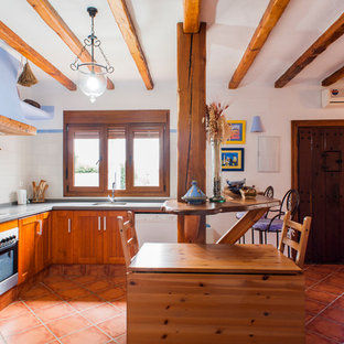 Ejemplo de cocina en L, mediterránea, con armarios con paneles empotrados, puertas de armario de madera oscura, salpicadero blanco, electrodomésticos blancos, península, suelo rojo y encimeras grises