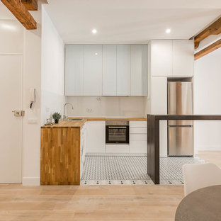 Diseño de cocina en L, nórdica, de tamaño medio, abierta, con armarios con paneles lisos, encimera de madera, salpicadero blanco, salpicadero de vidrio templado, electrodomésticos de acero inoxidable, suelo de baldosas de cerámica, península, suelo multicolor, fregadero encastrado y puertas de armario azules