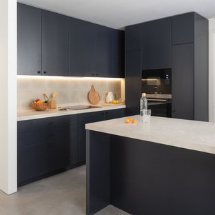 Foto de cocina en L, actual, con armarios con paneles lisos, puertas de armario negras, una isla, suelo gris y encimeras blancas