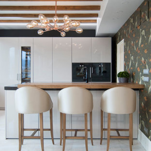Foto de cocina lineal, actual, grande, abierta, con fregadero bajoencimera, armarios con paneles lisos, puertas de armario beige, encimera de cuarcita, electrodomésticos negros, suelo de mármol, una isla, suelo beige y encimeras marrones