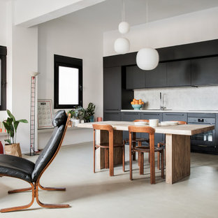 Ejemplo de cocina lineal, escandinava, abierta, con armarios con paneles lisos, puertas de armario negras, salpicadero verde, electrodomésticos negros, suelo de cemento, suelo gris y encimeras grises