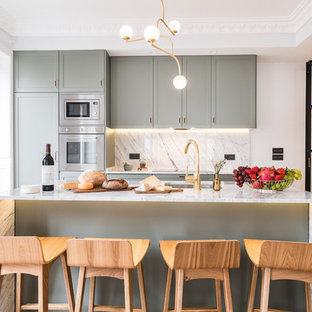 Ejemplo de cocina comedor de galera, actual, con fregadero bajoencimera, armarios estilo shaker, puertas de armario verdes, encimera de mármol, salpicadero verde, salpicadero de mármol, electrodomésticos de acero inoxidable, suelo de madera clara, una isla, suelo beige y encimeras grises