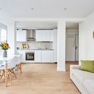 Ejemplo de cocina lineal, contemporánea, abierta, sin isla, con armarios con paneles lisos, puertas de armario blancas, electrodomésticos de acero inoxidable, suelo de madera clara, suelo beige y encimeras grises