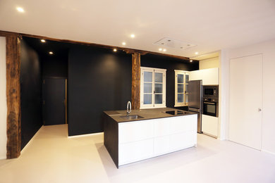 Foto de cocina contemporánea de tamaño medio abierta con armarios con paneles lisos, suelo de linóleo, una isla, suelo gris, encimeras negras y vigas vistas
