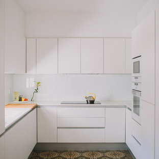 Imagen de cocina en U, moderna, pequeña, sin isla, con armarios con paneles lisos, puertas de armario blancas, salpicadero blanco, suelo multicolor y encimeras blancas