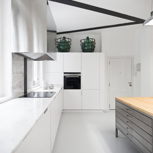 Diseño de cocina en L, industrial, cerrada, con armarios con paneles lisos, puertas de armario blancas, salpicadero blanco, suelo de cemento, una isla, suelo gris, encimeras blancas y electrodomésticos con paneles