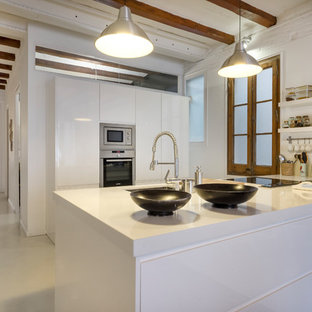 Diseño de cocina lineal, mediterránea, grande, abierta, con armarios con paneles lisos, puertas de armario blancas, electrodomésticos de acero inoxidable, península, encimeras blancas, fregadero bajoencimera, suelo de cemento y suelo gris