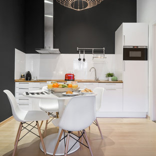 Ejemplo de cocina comedor lineal, contemporánea, de tamaño medio, sin isla, con armarios con paneles lisos, puertas de armario blancas, encimera de madera, salpicadero blanco, suelo de madera clara, encimeras marrones, fregadero encastrado, electrodomésticos con paneles y suelo beige