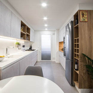 Diseño de cocina comedor de galera, actual, sin isla, con armarios con paneles lisos, salpicadero blanco, encimeras blancas, fregadero bajoencimera, puertas de armario grises, electrodomésticos de acero inoxidable y suelo gris