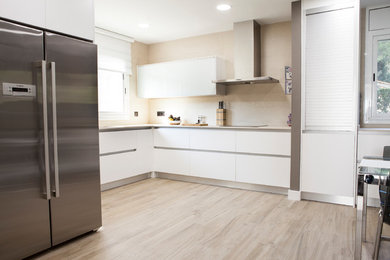 Modelo de cocina contemporánea grande con armarios con paneles lisos, puertas de armario blancas y suelo de madera clara