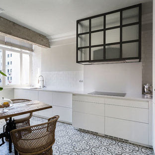 Imagen de cocina comedor lineal, tradicional renovada, de tamaño medio, sin isla, con fregadero bajoencimera, armarios con paneles lisos, puertas de armario blancas, salpicadero blanco, electrodomésticos negros, suelo de baldosas de cerámica, suelo multicolor y salpicadero de azulejos tipo metro