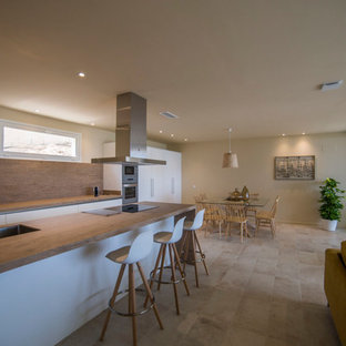 Ejemplo de cocina actual, abierta, con armarios con paneles lisos, puertas de armario blancas, electrodomésticos de acero inoxidable, una isla, fregadero de doble seno y suelo beige