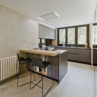 Foto de cocina en U, contemporánea, de tamaño medio, con armarios con paneles lisos, puertas de armario grises, península, suelo gris, encimera de madera y salpicadero negro