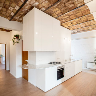 Ejemplo de cocina moderna, sin isla, con armarios con paneles lisos, puertas de armario blancas, salpicadero blanco, electrodomésticos de acero inoxidable y encimeras blancas