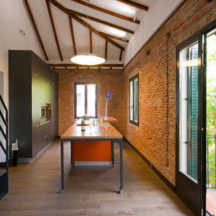 Foto de cocina industrial con armarios con paneles lisos, puertas de armario negras, encimera de madera, una isla y suelo marrón