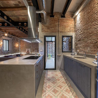 Diseño de cocina de galera y de obra, industrial, grande, abierta, con fregadero de un seno, armarios con paneles con relieve, puertas de armario grises, encimera de cemento, salpicadero beige, electrodomésticos de colores, suelo de baldosas de cerámica, península y encimeras grises