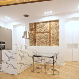 Modelo de cocina de galera, mediterránea, abierta, con armarios estilo shaker, puertas de armario grises, una isla, encimeras blancas, suelo de madera clara y suelo beige