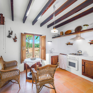 Immagine di una cucina a L country chiusa e di medie dimensioni con ante con bugna sagomata, ante in legno scuro, top in superficie solida, paraspruzzi bianco, elettrodomestici in acciaio inossidabile, pavimento in terracotta e nessuna isola