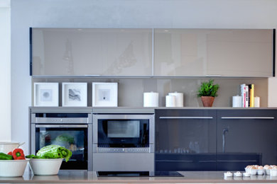 Imagen de cocina lineal contemporánea de tamaño medio abierta con armarios con paneles lisos y una isla