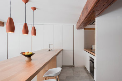 Diseño de cocina lineal abierta con encimera de madera, una isla y suelo gris
