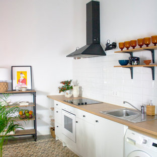 Imagen de cocina lineal, actual, pequeña, sin isla, con fregadero encastrado, armarios con paneles lisos, puertas de armario blancas, encimera de madera, salpicadero blanco, salpicadero de azulejos de porcelana, electrodomésticos blancos, suelo marrón y encimeras beige