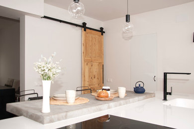 Photo of a medium sized mediterranean kitchen/diner in Barcelona with white cabinets, limestone worktops and an island.