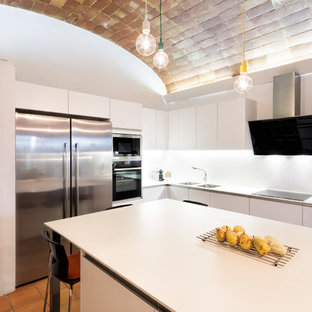 Modelo de cocina en L, minimalista, de tamaño medio, con fregadero de doble seno, armarios con paneles lisos, puertas de armario blancas, encimera de cuarzo compacto, salpicadero blanco, electrodomésticos de acero inoxidable, suelo de baldosas de terracota, una isla, suelo marrón y encimeras blancas