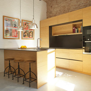 Imagen de cocina comedor de galera, mediterránea, de tamaño medio, con puertas de armario de madera oscura, salpicadero negro, electrodomésticos negros, suelo de cemento, una isla, suelo gris, encimeras negras, fregadero bajoencimera y armarios con paneles lisos