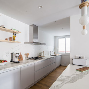 Ejemplo de cocina lineal, escandinava, con fregadero de un seno, armarios con paneles lisos, puertas de armario grises, encimera de mármol, salpicadero blanco, salpicadero de mármol, suelo de madera en tonos medios, península y encimeras blancas