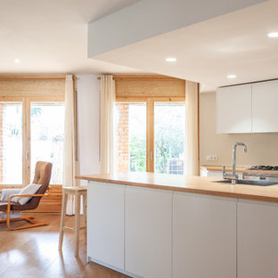 Immagine di una piccola cucina minimal con lavello a vasca singola, ante lisce, ante bianche, top in legno, paraspruzzi bianco, elettrodomestici in acciaio inossidabile, pavimento in legno massello medio, isola, pavimento marrone e top marrone