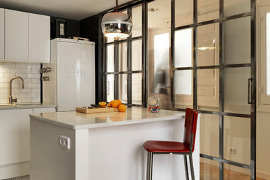 Small urban single-wall enclosed kitchen in Madrid with a submerged sink, flat-panel cabinets, white cabinets, white splashback, ceramic splashback, ceramic flooring, an island and white floors.