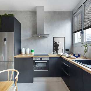 Diseño de cocina comedor en L, contemporánea, sin isla, con armarios con paneles lisos, encimera de madera, electrodomésticos de acero inoxidable, fregadero de doble seno, puertas de armario negras y suelo gris