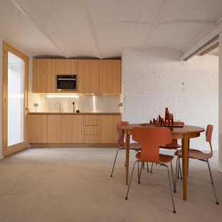 Imagen de cocina comedor lineal, contemporánea, pequeña, sin isla, con armarios con paneles lisos, puertas de armario de madera clara, electrodomésticos de acero inoxidable, suelo de cemento y suelo gris