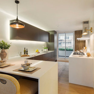 Modelo de cocina en U, contemporánea, de tamaño medio, cerrada, con armarios con paneles lisos, puertas de armario marrones, salpicadero blanco, suelo de madera en tonos medios, península, suelo marrón, encimeras blancas y fregadero bajoencimera