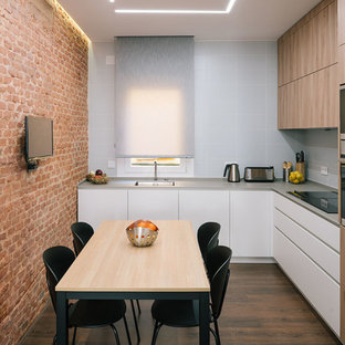 Imagen de cocina en L, actual, con fregadero bajoencimera, armarios con paneles lisos, puertas de armario grises, salpicadero blanco, salpicadero de azulejos tipo metro, electrodomésticos de acero inoxidable, suelo de madera oscura y suelo marrón