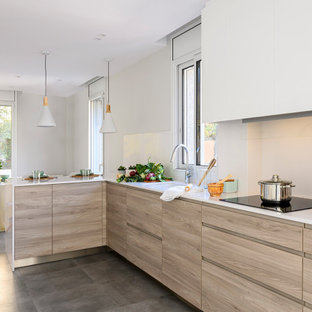 Foto de cocina comedor bandeja y en L, actual, de tamaño medio, con fregadero bajoencimera, armarios con paneles lisos, encimera de cuarcita, salpicadero blanco, salpicadero de piedra caliza, electrodomésticos de acero inoxidable, suelo de baldosas de cerámica, península, suelo gris, encimeras blancas y puertas de armario de madera clara