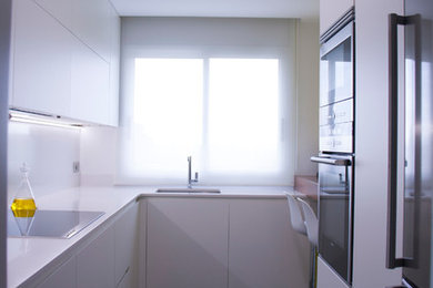 Diseño de cocinas en L moderna de tamaño medio cerrada sin isla con armarios con paneles lisos y puertas de armario blancas