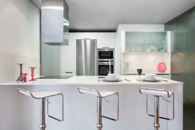 Modelo de cocina contemporánea de tamaño medio abierta con fregadero encastrado, salpicadero blanco, electrodomésticos de acero inoxidable y una isla