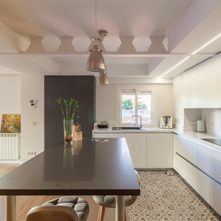 Modelo de cocina en L, actual, de tamaño medio, abierta, con armarios con paneles lisos, puertas de armario blancas, salpicadero blanco, electrodomésticos con paneles, suelo de baldosas de cerámica, una isla, suelo multicolor y fregadero de un seno
