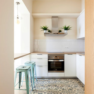 Ejemplo de cocina en U, contemporánea, de tamaño medio, abierta, con armarios con paneles lisos, puertas de armario blancas, encimera de madera, salpicadero blanco, salpicadero de azulejos de cerámica, electrodomésticos de acero inoxidable, suelo de baldosas de cerámica, península y suelo multicolor