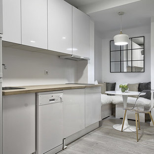 Modelo de cocina comedor lineal, escandinava, sin isla, con fregadero encastrado, armarios con paneles lisos, puertas de armario blancas, encimera de madera, salpicadero blanco, electrodomésticos blancos, suelo gris, encimeras beige y suelo de madera clara