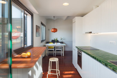 Modelo de cocina lineal mediterránea con puertas de armario blancas, electrodomésticos de acero inoxidable y encimeras verdes