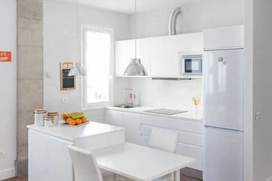 他の地域にあるお手頃価格の小さなインダストリアルスタイルのおしゃれなキッチン (シングルシンク、フラットパネル扉のキャビネット、白いキャビネット、白いキッチンパネル、白い調理設備、濃色無垢フローリング) の写真