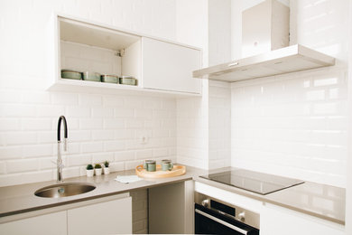 バルセロナにあるお手頃価格の小さなコンテンポラリースタイルのおしゃれなキッチン (アンダーカウンターシンク、白いキッチンパネル、セラミックタイルのキッチンパネル、シルバーの調理設備、セラミックタイルの床、黒い床、グレーのキッチンカウンター) の写真
