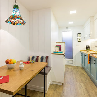 Foto de cocina comedor lineal, tradicional renovada, de tamaño medio, sin isla, con fregadero bajoencimera, armarios con paneles empotrados, encimera de madera, salpicadero blanco, salpicadero de azulejos tipo metro, electrodomésticos de acero inoxidable, suelo de madera en tonos medios, suelo marrón y puertas de armario azules