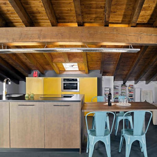 Foto de cocina de galera, actual, grande, con armarios con paneles lisos, una isla, suelo negro y puertas de armario amarillas
