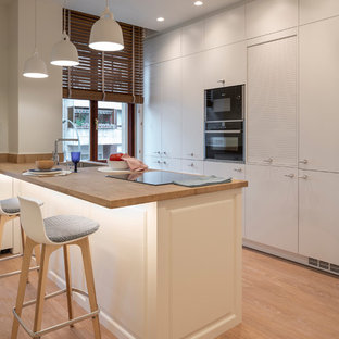 Imagen de cocina en U, contemporánea, grande, con armarios con paneles lisos, puertas de armario blancas, península, fregadero bajoencimera, electrodomésticos con paneles, suelo marrón, encimeras marrones, encimera de madera y suelo de madera clara