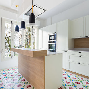 Foto de cocina en L, actual, de tamaño medio, abierta, con suelo de baldosas de cerámica, una isla, armarios con paneles con relieve, puertas de armario blancas y suelo multicolor